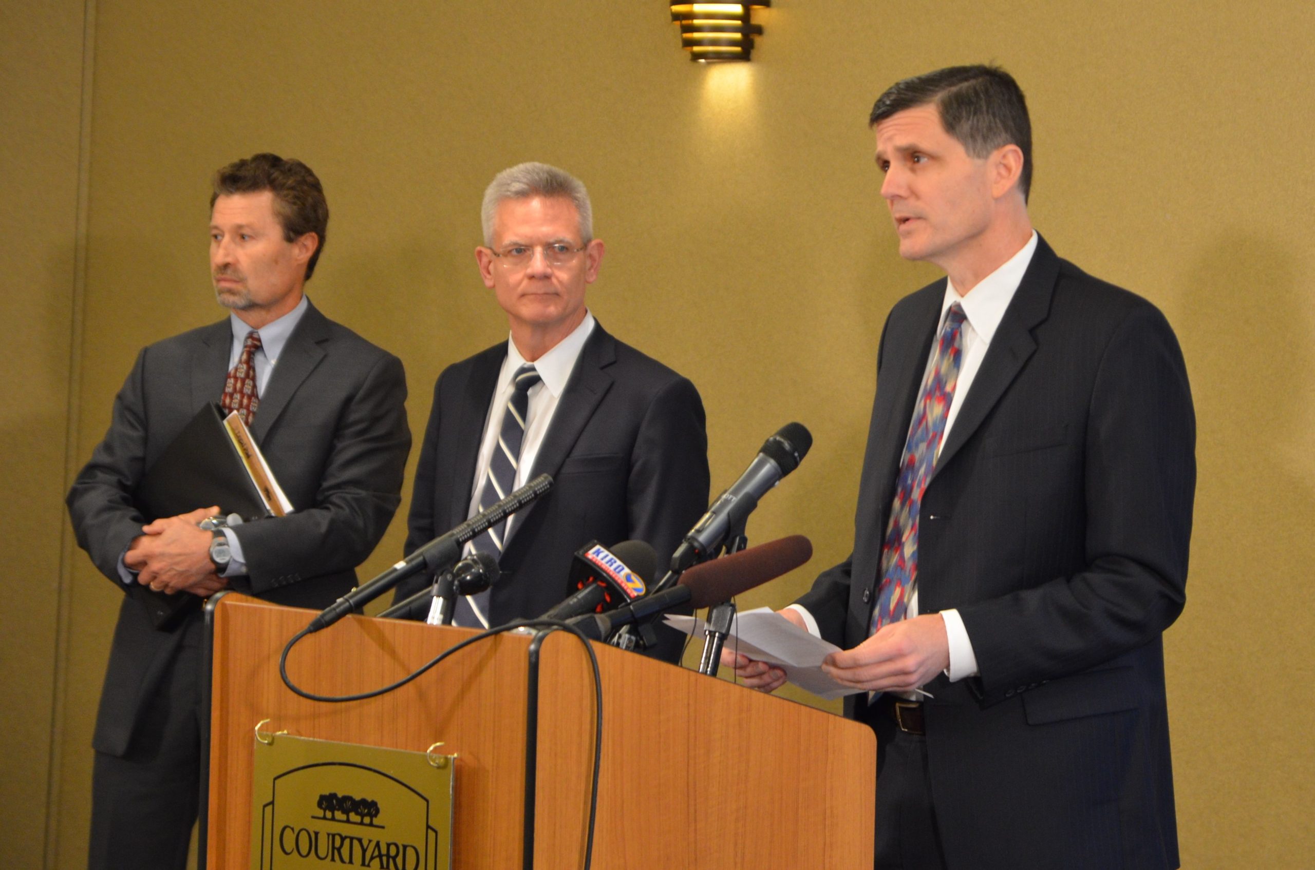State Auditor Troy Kelley, behind the podium, addresses reporters as his attorneys (l-r) Rob McCallum and Mark Bartlett, look on. (Photo by Venice Buhain)