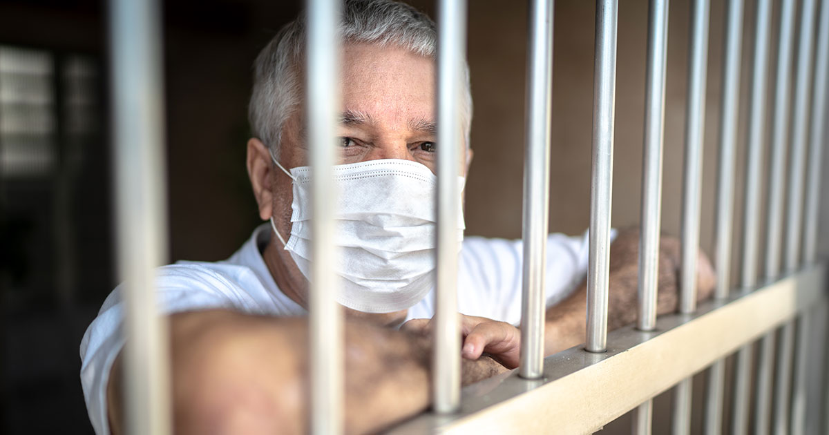 masked prisoner behind bars